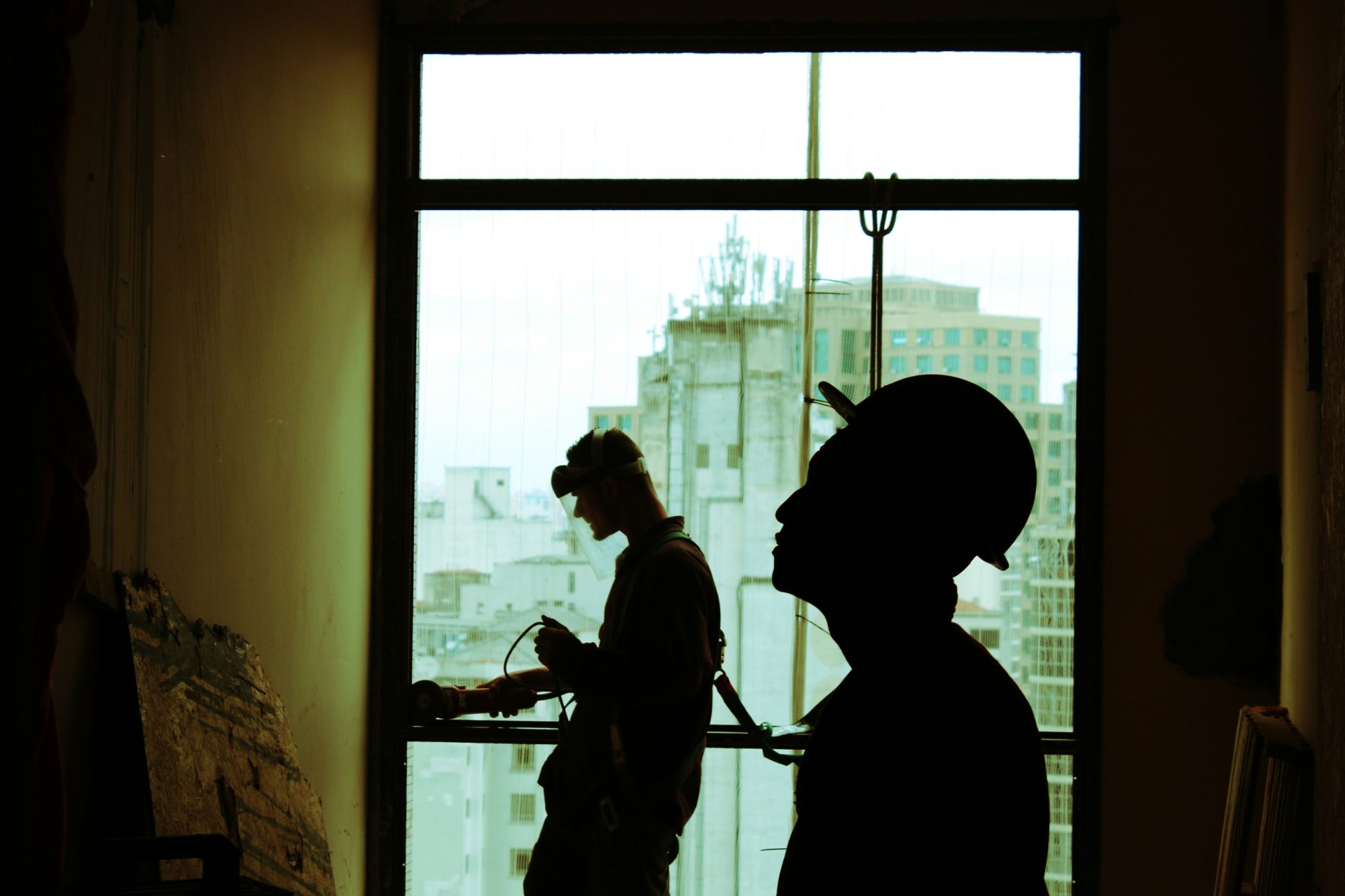 Silhouetted construction workers inside high-rise building.