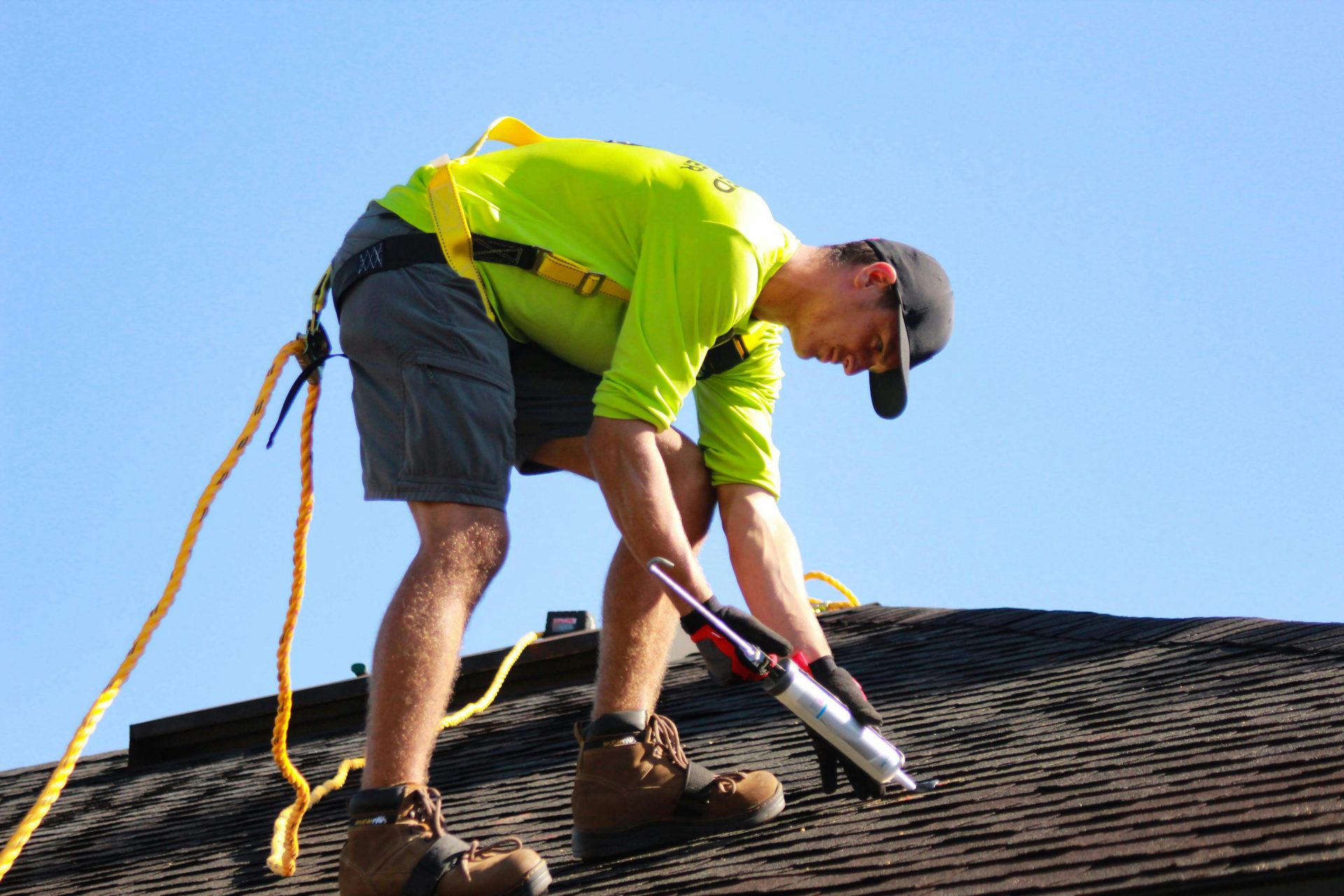 Worker applying sealant on shingled rooftop