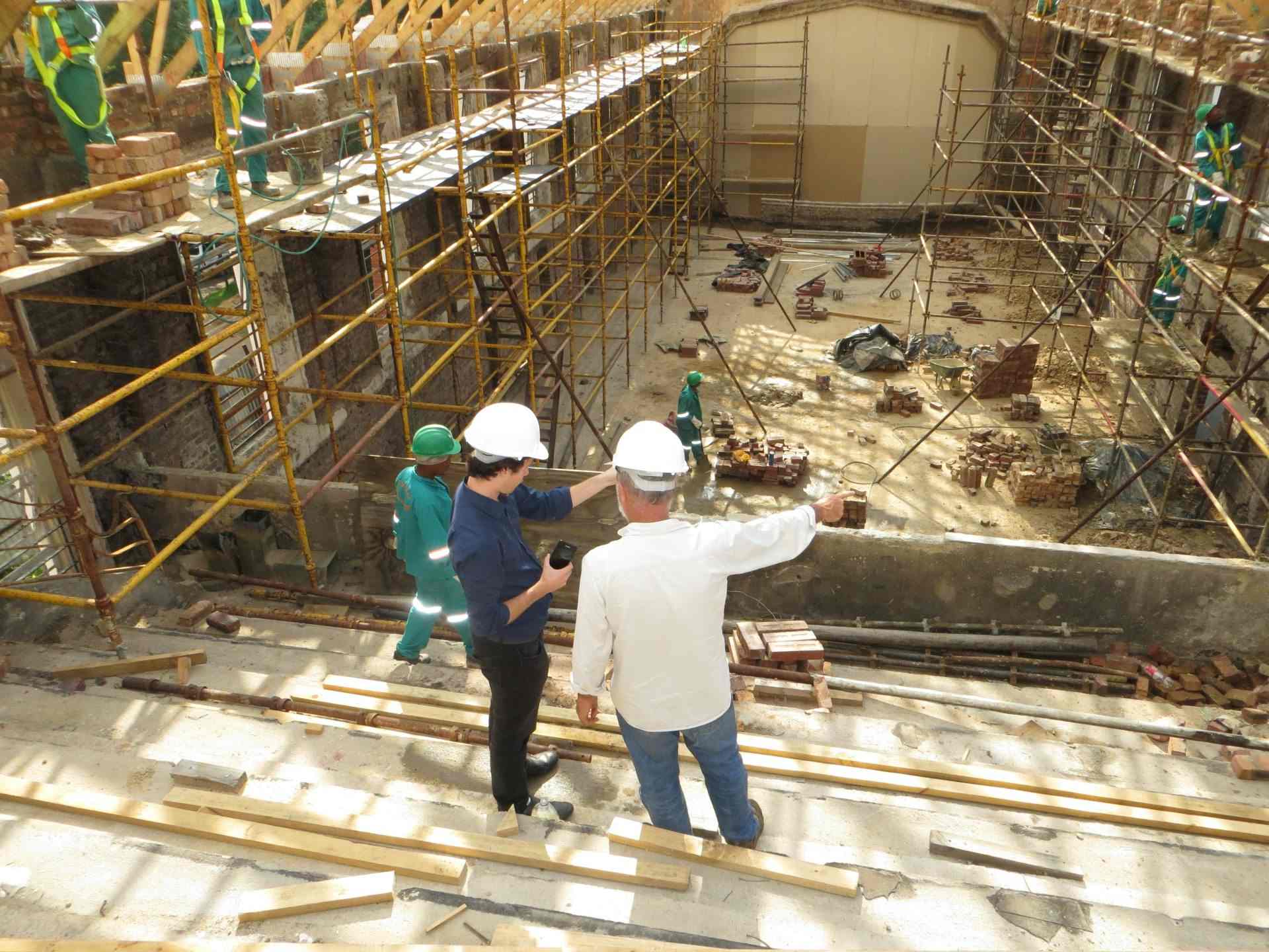 Construction supervisors inspecting site with scaffolding.